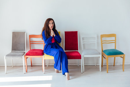 Woman in blue clothes and many different chairsの写真素材