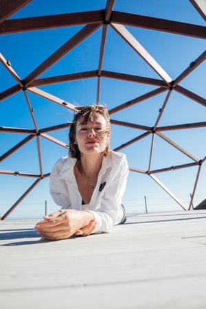 Beautiful fashionable woman posing by wooden structureの写真素材