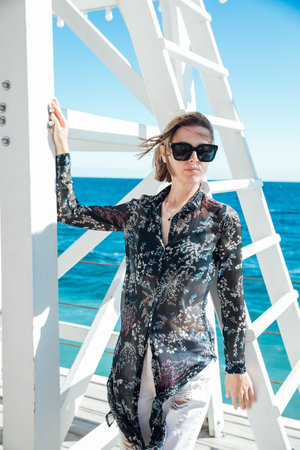 Fashionable woman on a walk near the sea at the rescue towerの写真素材