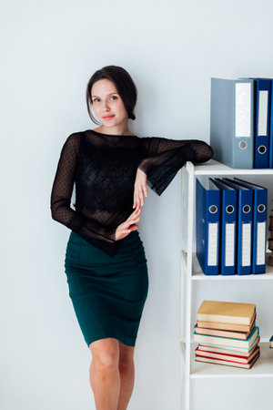 A business woman in the office stands at the shelves with foldersの写真素材