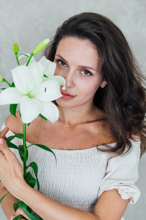 Portrait of a beautiful brunette woman with lily flowersの写真素材