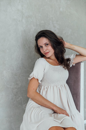 Woman in white dress sitting in bright roomの写真素材