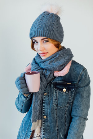 woman in winter clothes on white background with a mug of coffeeの写真素材