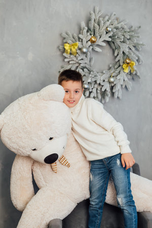 Boy with bear toy at christmas tree with gifts for new yearの写真素材