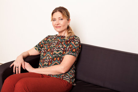 Woman sitting on couch in bright roomの写真素材