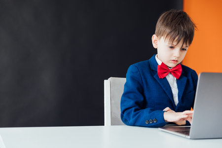 Business boy in jacket sitting at laptopの写真素材