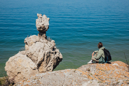a woman on a cliff looks at the sea in a hike journey natureの写真素材