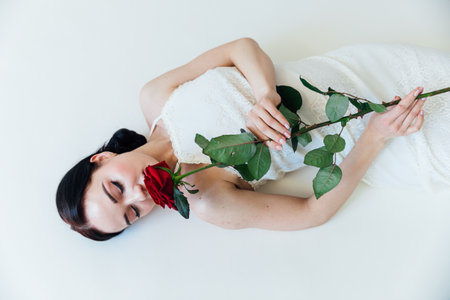 beautiful woman in a white wedding dress with a rose flowerの写真素材