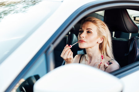 Woman painting lips while driving a car Travel