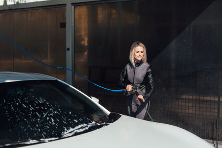 Beautiful woman washing car at car washの写真素材