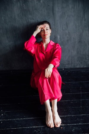 Woman in silk pajamas sitting on the floor in a roomの写真素材