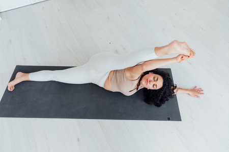 Attractive young woman doing yoga stretching yoga online at home. Self-isolation is beneficial,の写真素材