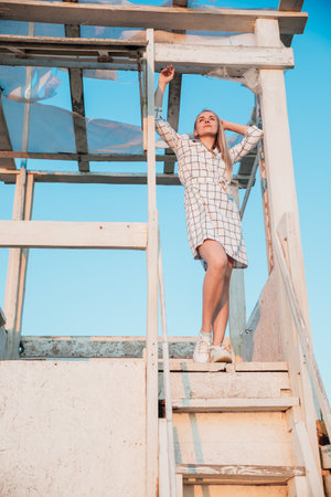 beautiful blonde stands on the wooden stairs of the houseの写真素材