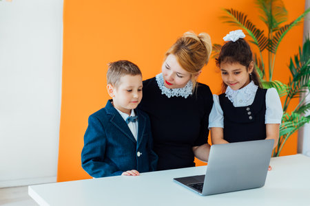 Teacher teaching boy and girl on computer at schoolの写真素材