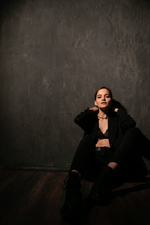 Woman in black clothes posing in a dark roomの写真素材