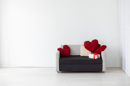 A sofa with a heart-shaped pillow and gifts in a bright roomの写真素材