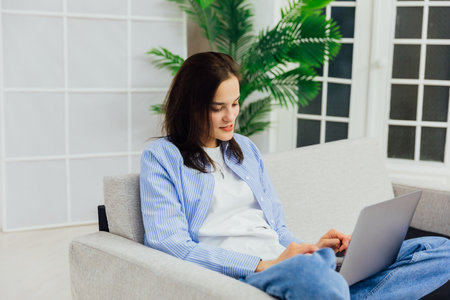 Woman sitting on couch with notebook online jobの写真素材