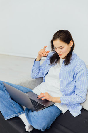 Woman sitting on couch with notebook online jobの写真素材