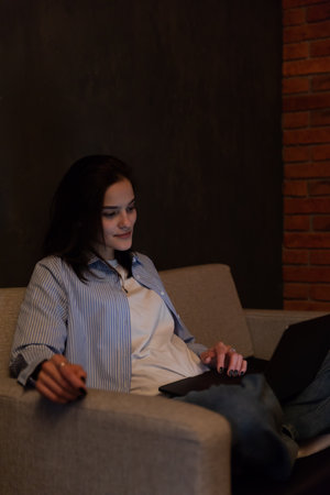Woman sitting on sofa with computer chatting online jobの写真素材