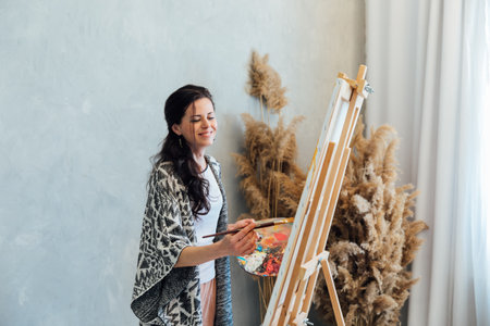 The artist paints a picture on an easel in the studioの写真素材