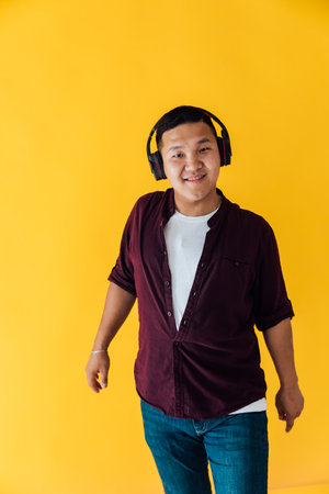 A man listens to music with headphones and dances on a yellow backgroundの写真素材