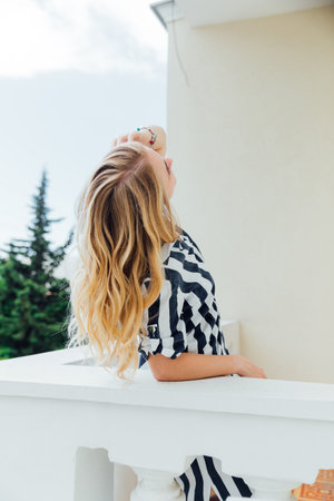 woman in striped dress standing on balcony looking at streetの写真素材