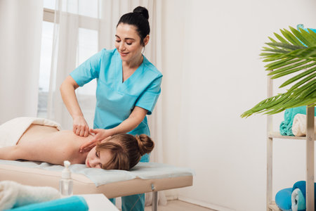 Masseuse doing a therapeutic relaxing back massage to a girl in the spaの写真素材