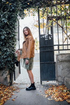 Beautiful woman walking in autumn city with fallen leavesの写真素材