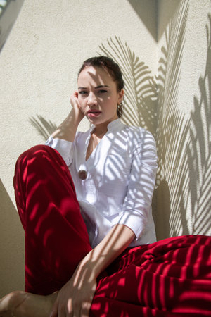 Beautiful fashionable brunette woman and shadow from leaves in the sunの写真素材