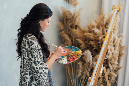 Woman artist painting with paints beautiful pictureの写真素材
