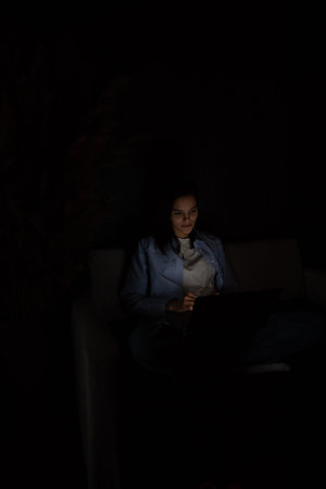 Woman working remotely online on laptop from sofa at homeの写真素材