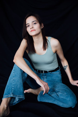 Beautiful young slender woman in jeans sittingの写真素材