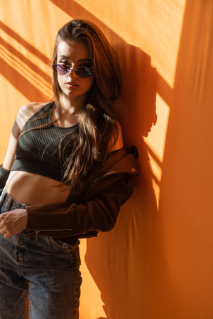 Beautiful slender brunette woman sun on orangeの写真素材