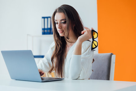 Cheerful business lady working on laptop in office,の写真素材