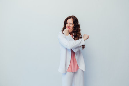 Beautiful brunette woman clenched her fists on a white backgroundの写真素材