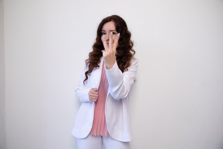 Beautiful brunette woman showing three fingers on white backgroundの写真素材