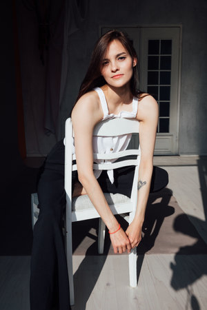 Portrait of a beautiful young slender woman sitting on a chairの写真素材