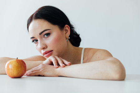 Beautiful brunette woman with apple in bright roomの写真素材