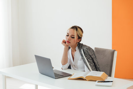 Image of young pleased happy cheerful cute beautiful business woman sit indoors in office using laptop computerの写真素材