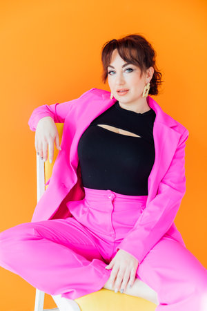 Portrait of a beautiful young woman in a purple business suit on a chairの写真素材