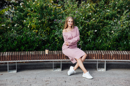 Beautiful slender blonde woman in pink clothes on a walk outdoorsの写真素材