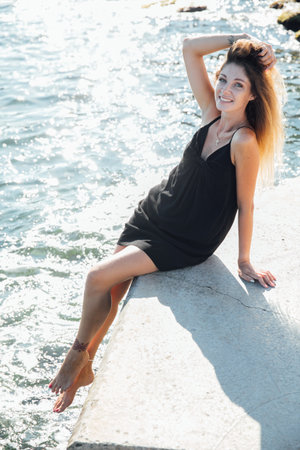 Beautiful slender fashionable woman in black summer dress walking on the streets of the cityの写真素材