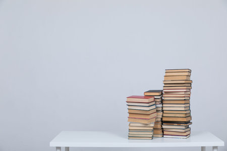 A simple composition of many books, stack or pile of books on wooden table, one of them open with...