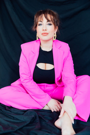 Woman sitting in bright suit on black backgroundの写真素材