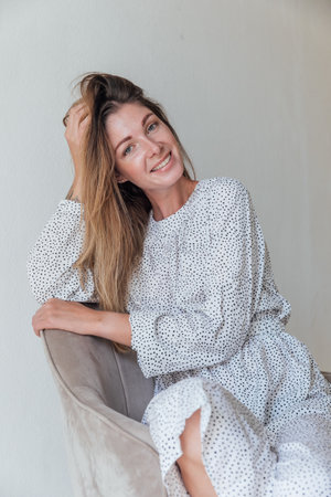 Cheerful woman on an armchair in a bright roomの写真素材