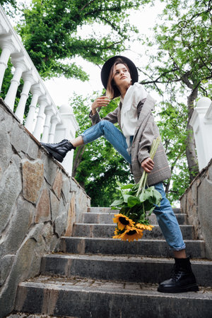 Woman in a hat on a walk with a bouquet of sunflowersの写真素材