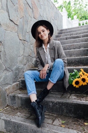 Woman in a hat with flowers posing for a walk near the houseの写真素材
