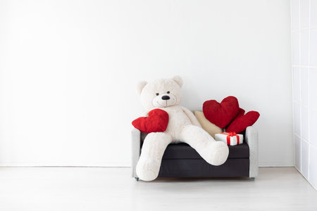 A sofa with heart-shaped pillows with a toy and gifts in a bright roomの写真素材