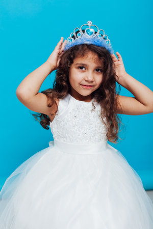 Girl in a white elegant dress with a crown on a blue background Holidayの写真素材