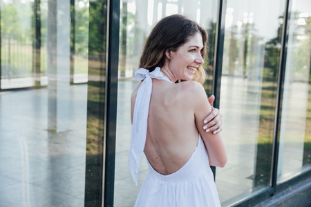 Portrait of a beautiful smiling woman in a summer light dress in the park on a walkの写真素材